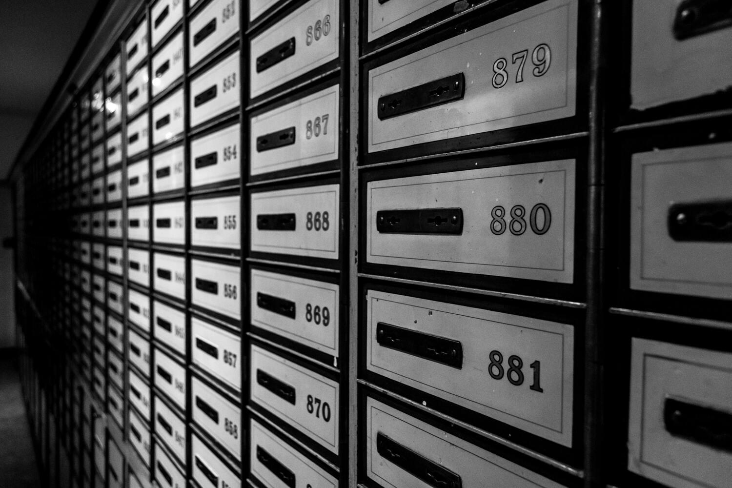 Editorial architectural photograph of a row of numbered brass office signs on a panelled wall, calm Swiss interior